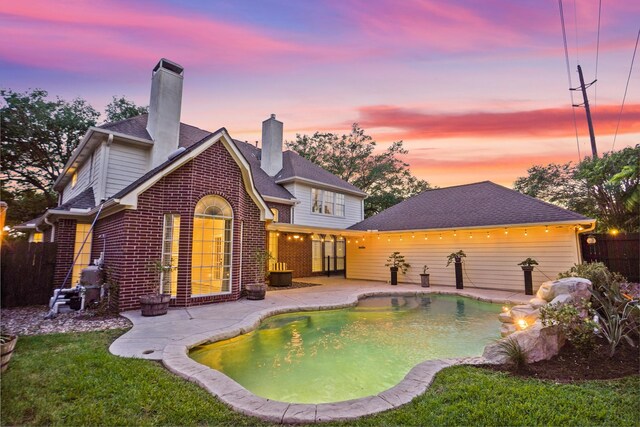 rear view of property with a chimney, fence, a patio, a fenced in pool, and brick siding