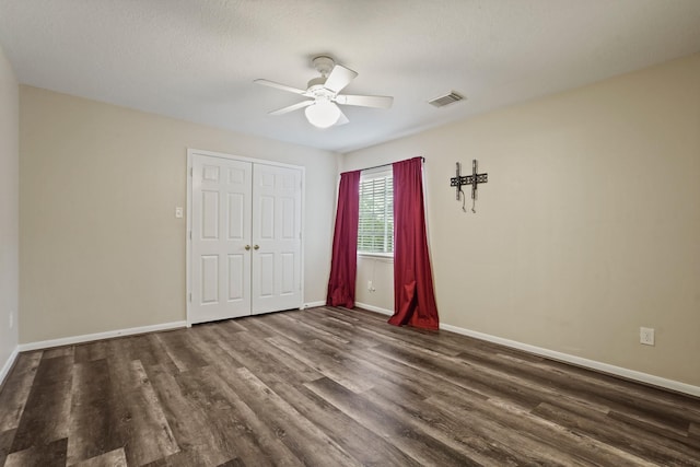 unfurnished bedroom featuring a closet, baseboards, visible vents, and dark wood-style floors