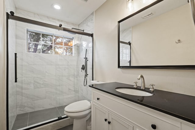 bathroom featuring toilet, vanity, visible vents, and a stall shower