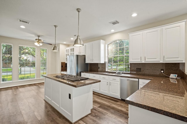 kitchen featuring dark countertops, a healthy amount of sunlight, stainless steel appliances, and a sink