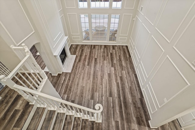 unfurnished living room with stairway, a decorative wall, and dark wood-style flooring