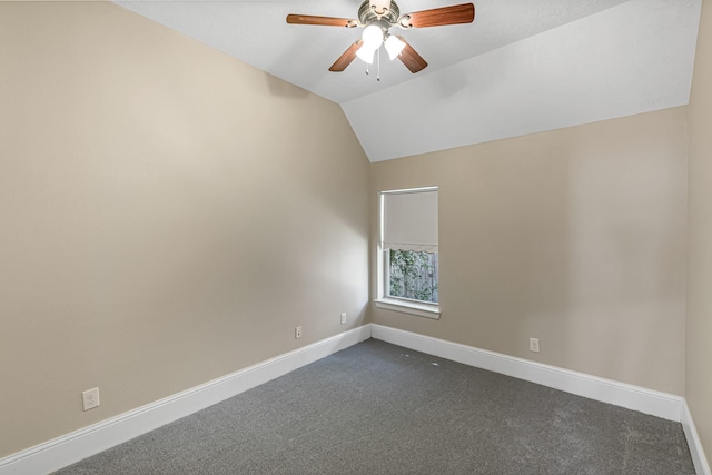 spare room featuring lofted ceiling, dark colored carpet, baseboards, and ceiling fan