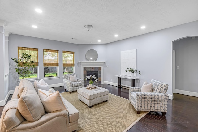 living area featuring baseboards, arched walkways, a textured ceiling, and recessed lighting