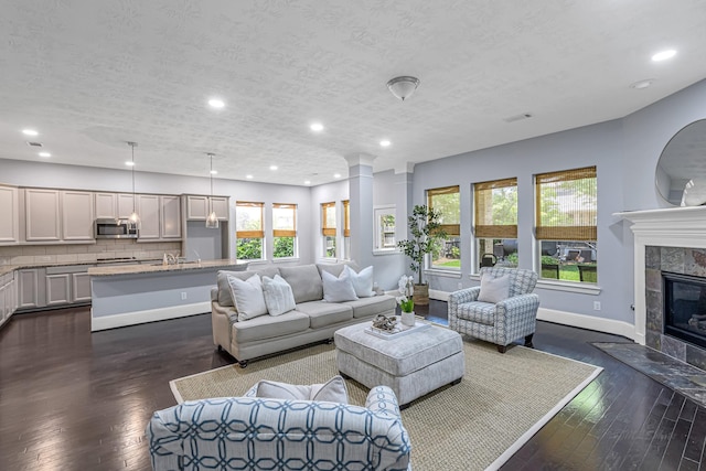 living area featuring recessed lighting, dark wood finished floors, visible vents, baseboards, and a fireplace