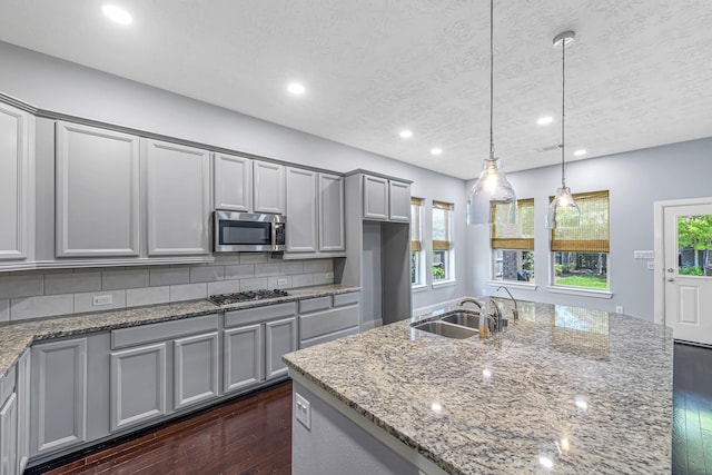 kitchen featuring stainless steel appliances, a sink, dark wood finished floors, tasteful backsplash, and gray cabinets
