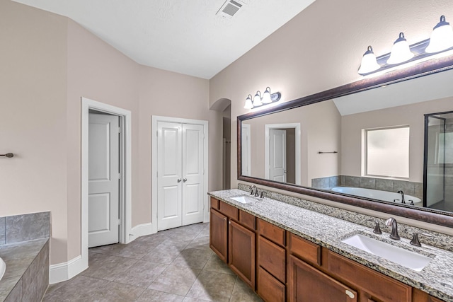 bathroom featuring a bath, visible vents, a sink, and double vanity