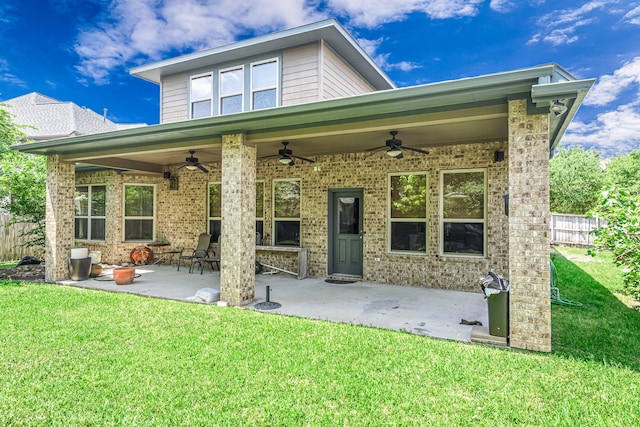 back of property with fence, ceiling fan, a yard, and a patio area