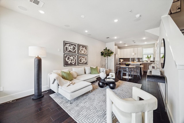 living area featuring baseboards, dark wood-type flooring, visible vents, and recessed lighting
