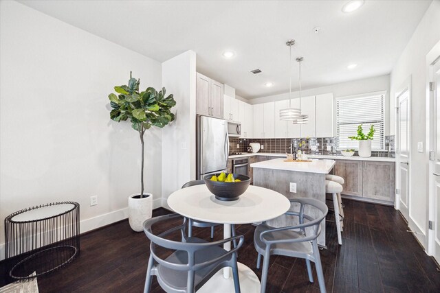 kitchen with stainless steel appliances, dark wood-style floors, decorative backsplash, light countertops, and a kitchen island