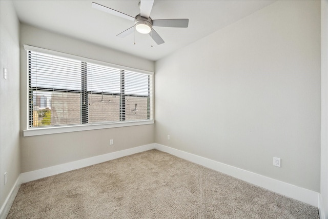 carpeted empty room featuring baseboards and a ceiling fan