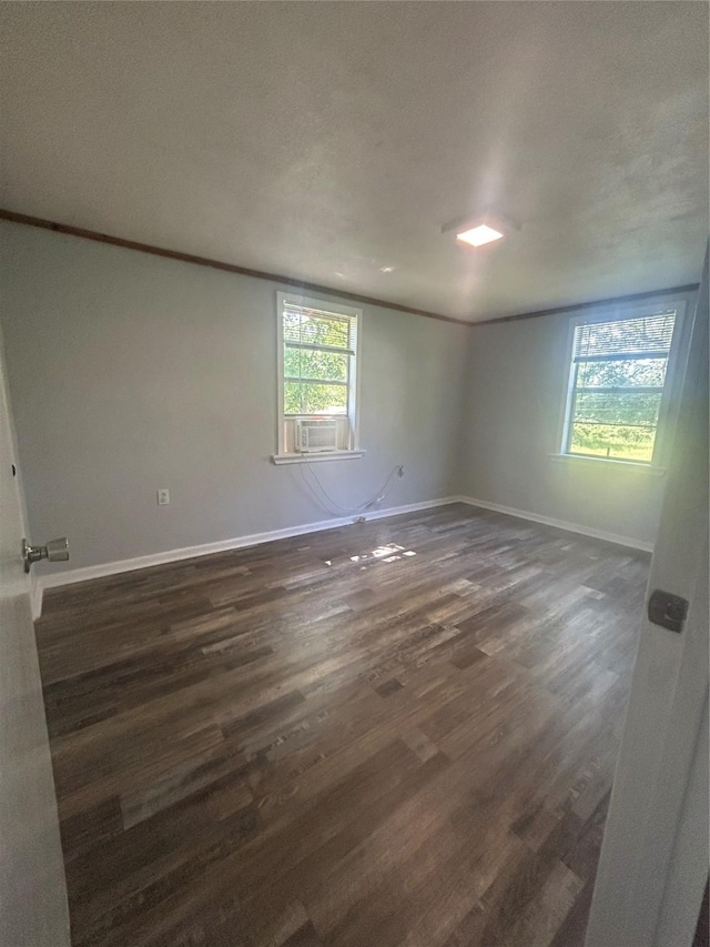 unfurnished room featuring dark wood finished floors, baseboards, and ornamental molding