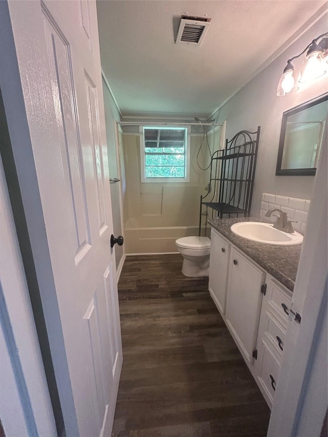 full bath featuring wood finished floors, vanity, shower / washtub combination, toilet, and visible vents