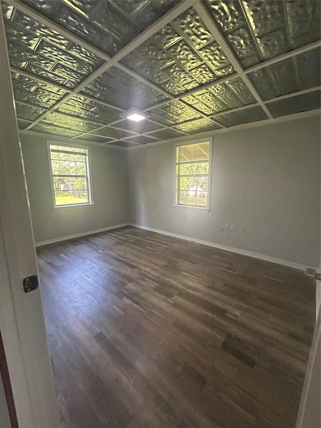 interior space featuring baseboards, an ornate ceiling, wood finished floors, and plenty of natural light