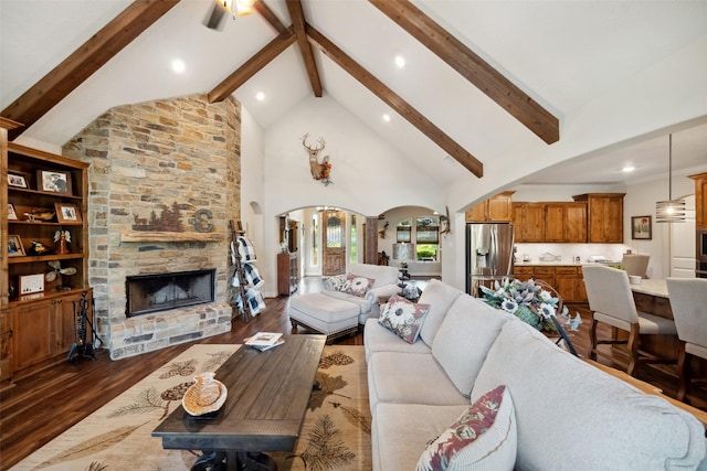 living area with arched walkways, dark wood finished floors, beamed ceiling, a stone fireplace, and high vaulted ceiling