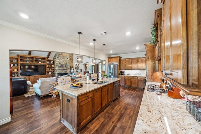 kitchen with crown molding, a stone fireplace, a sink, appliances with stainless steel finishes, and visible vents