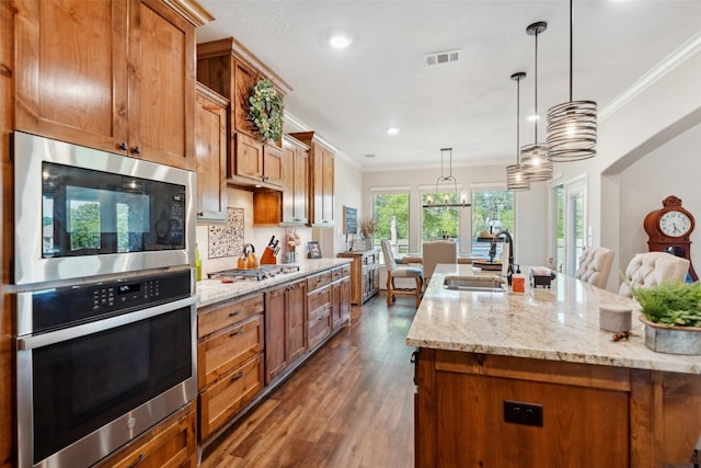 kitchen featuring dark wood-style flooring, ornamental molding, stainless steel appliances, and a sink