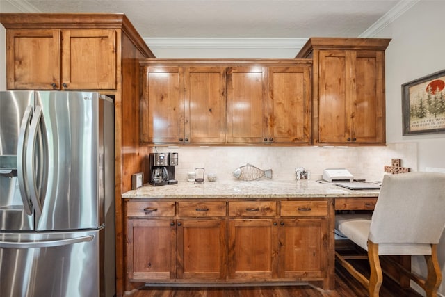 kitchen featuring built in desk, crown molding, brown cabinets, and stainless steel fridge with ice dispenser