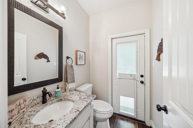 bathroom featuring wood finished floors, toilet, and vanity