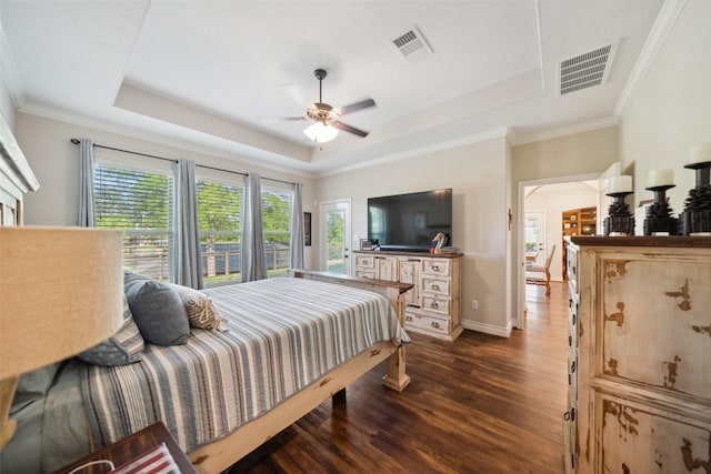 bedroom with visible vents, dark wood finished floors, and a tray ceiling