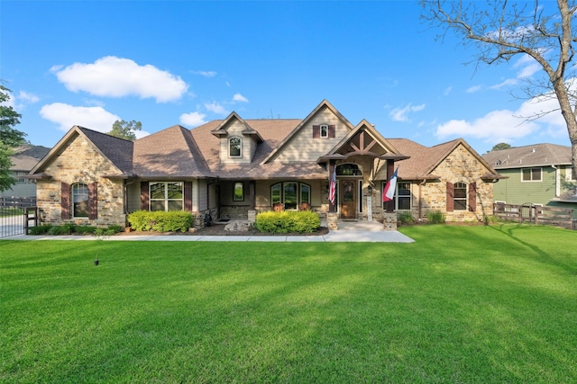 craftsman-style house featuring stone siding, fence, a front yard, and roof with shingles