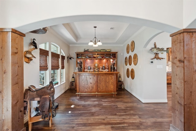 bar featuring a bar, wood finished floors, arched walkways, and a raised ceiling