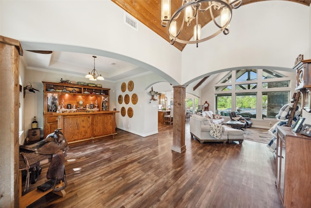living area featuring arched walkways, an inviting chandelier, baseboards, dark wood-style floors, and decorative columns
