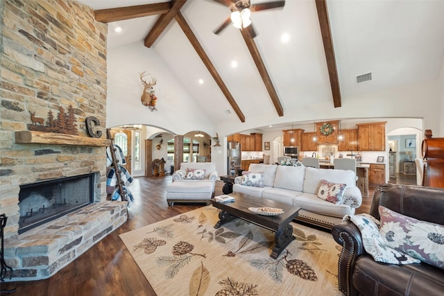 living area with beamed ceiling, visible vents, arched walkways, and high vaulted ceiling