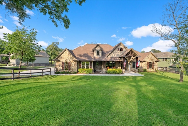 view of front of house with a porch, stone siding, a front yard, and fence