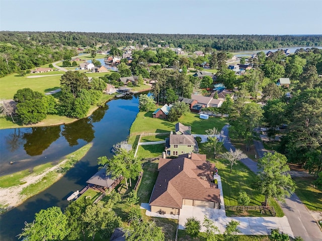 drone / aerial view featuring a wooded view, a residential view, and a water view