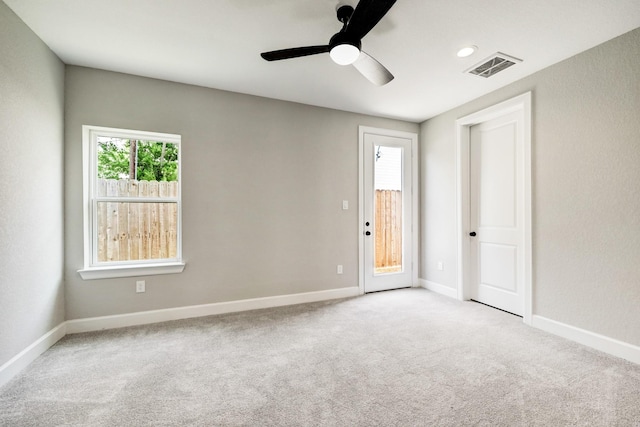 carpeted spare room featuring baseboards, a ceiling fan, and visible vents