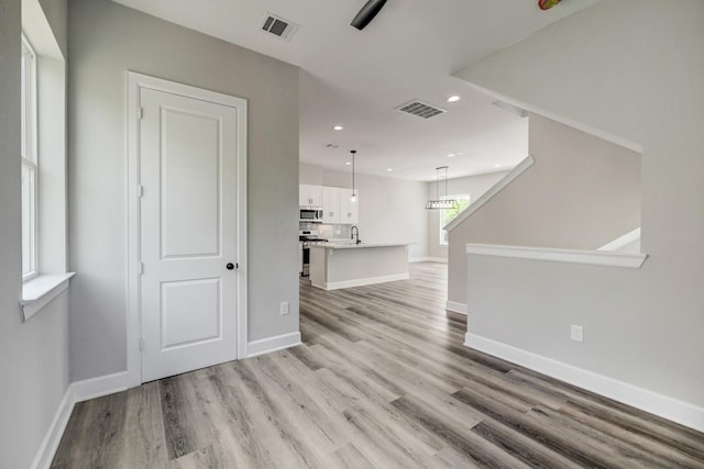 unfurnished living room with baseboards, light wood-style floors, and visible vents