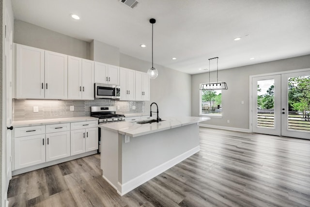 kitchen featuring stainless steel appliances, backsplash, a sink, light wood-type flooring, and white cabinetry