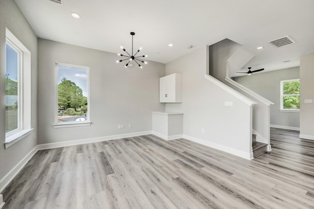 unfurnished living room with baseboards, stairs, visible vents, and light wood-style floors