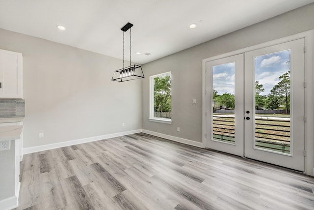 unfurnished dining area featuring baseboards, recessed lighting, french doors, and light wood-style flooring