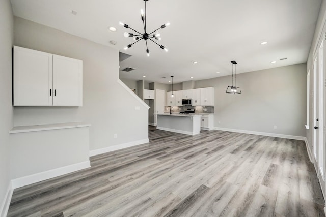 unfurnished living room featuring baseboards, recessed lighting, a chandelier, and light wood-style flooring