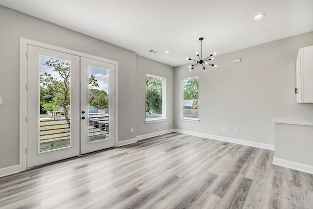 unfurnished dining area with visible vents, baseboards, an inviting chandelier, and light wood-style floors