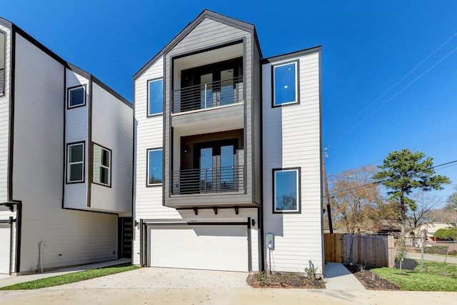 view of front facade with fence, concrete driveway, a balcony, and a garage