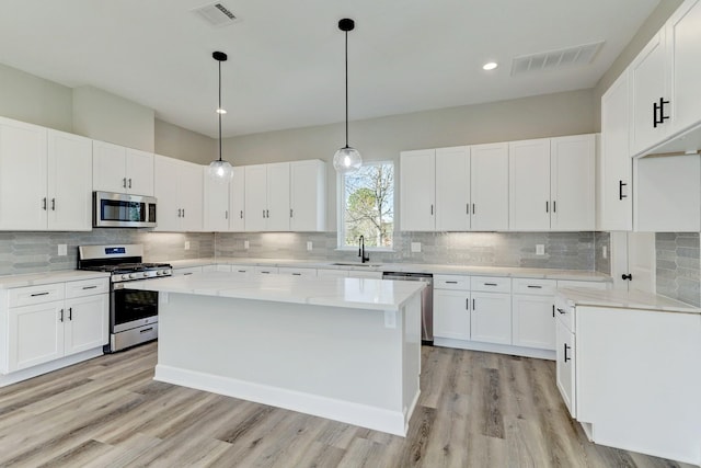 kitchen featuring visible vents, light wood finished floors, stainless steel appliances, and a sink
