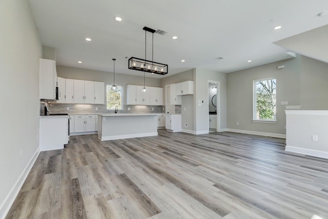 unfurnished living room with a wealth of natural light, visible vents, and light wood-type flooring