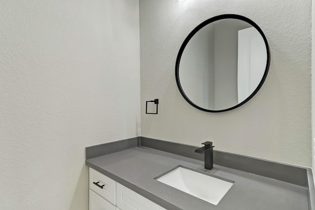 bathroom with a textured wall and vanity
