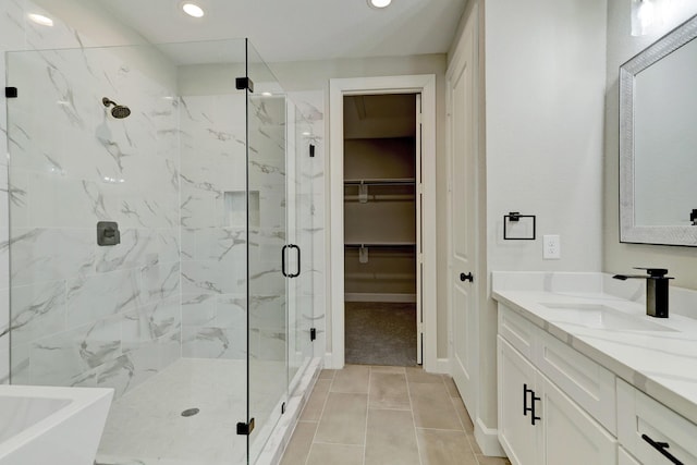 full bath featuring recessed lighting, tile patterned floors, vanity, a marble finish shower, and a walk in closet