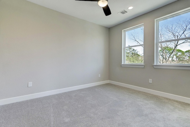 empty room featuring baseboards, visible vents, ceiling fan, and light colored carpet