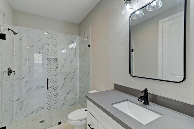 bathroom with toilet, vanity, and a marble finish shower