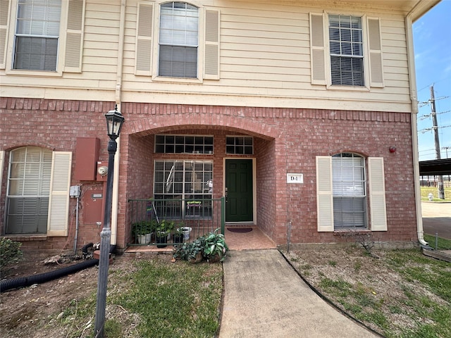 doorway to property with covered porch and brick siding
