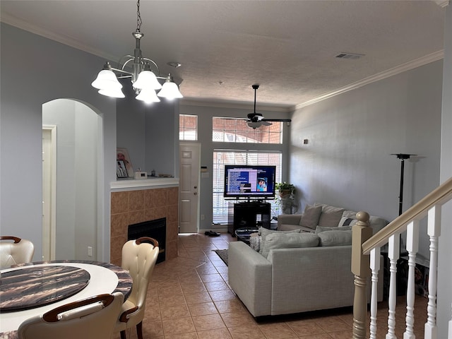 living room with crown molding, a tile fireplace, visible vents, and light tile patterned floors