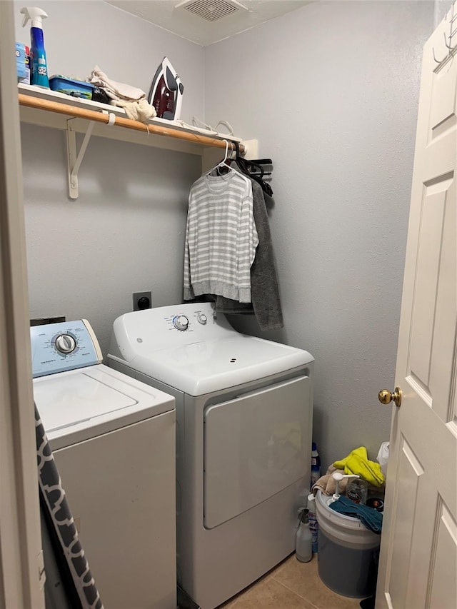 laundry room with separate washer and dryer, visible vents, tile patterned floors, and laundry area
