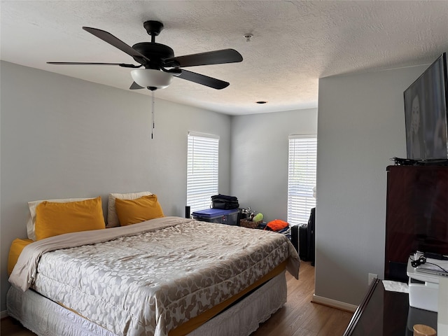 bedroom with baseboards, a ceiling fan, wood finished floors, and a textured ceiling