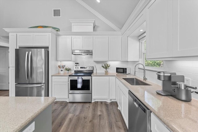 kitchen featuring a sink, vaulted ceiling, visible vents, under cabinet range hood, and appliances with stainless steel finishes