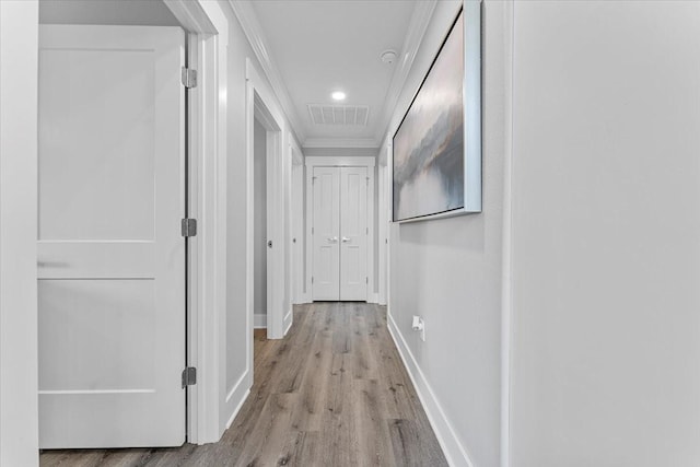 hall featuring recessed lighting, visible vents, ornamental molding, baseboards, and light wood-style flooring