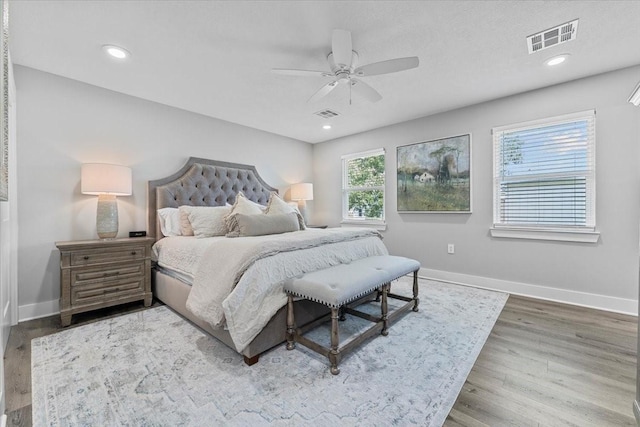 bedroom featuring baseboards, a ceiling fan, wood finished floors, and visible vents